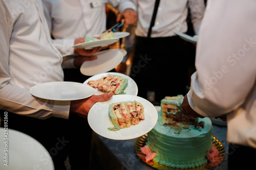 Young chefs cut the bride's cake in the dishes.