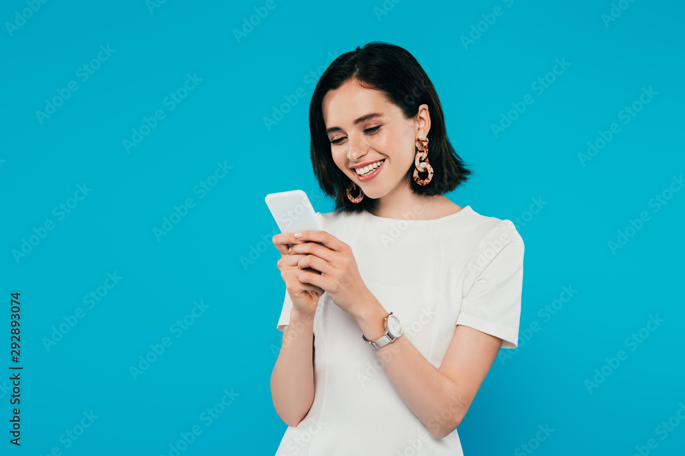 smiling elegant woman in dress using smartphone isolated on blue smiling elegant woman in dress using smartphone isolated on blue