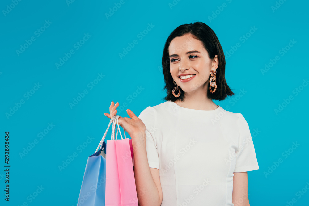 smiling elegant woman in dress with shopping bags looking away isolated on blue smiling elegant woman in dress with shopping bags looking away isolated on blue