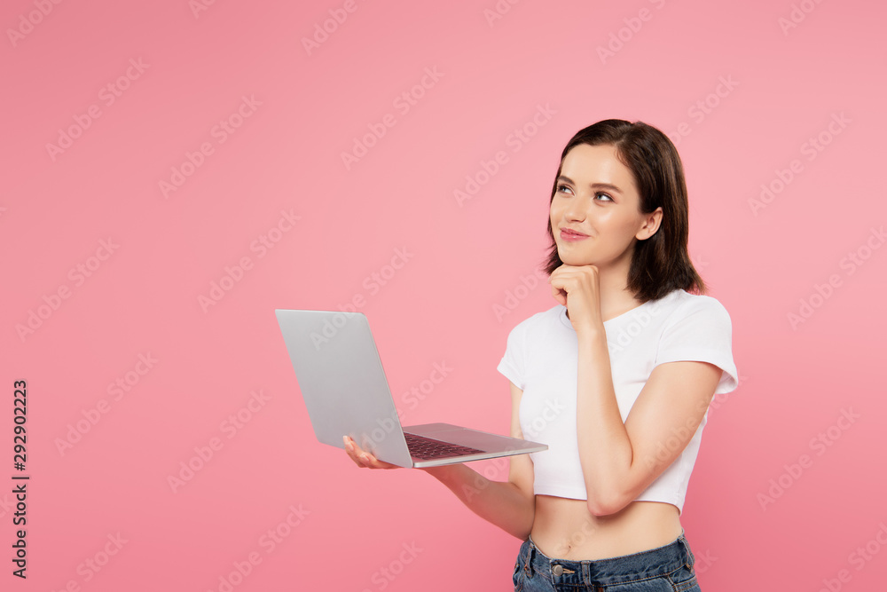 Fototapeta premium dreamy smiling pretty girl using laptop isolated on pink