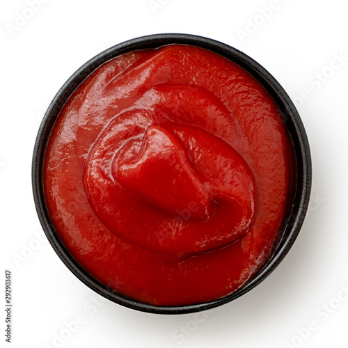 Tomato ketchup in small black ceramic dish isolated on white. Top view.