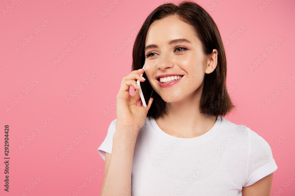 beautiful smiling girl talking on smartphone isolated on pink