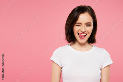 beautiful girl showing tongue and winking isolated on pink photo