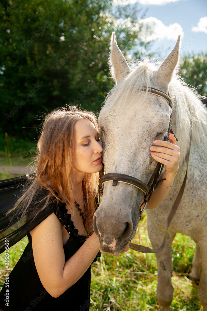 Fototapeta premium Beautiful caucasian young girl walking with a horse and enjoys summertime in countryside.