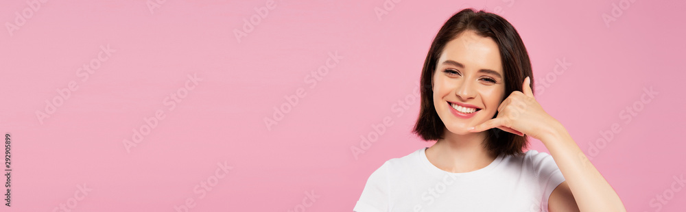 panoramic shot of beautiful smiling girl showing call me gesture isolated on pink panoramic shot of beautiful smiling girl showing call me gesture isolated on pink