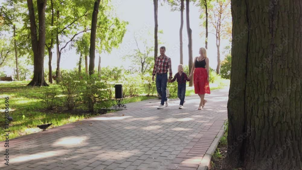 Happy young family walks in the park along the alley. Happy young family walks in the park along the alley.