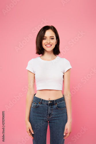 smiling pretty girl in jeans isolated on pink