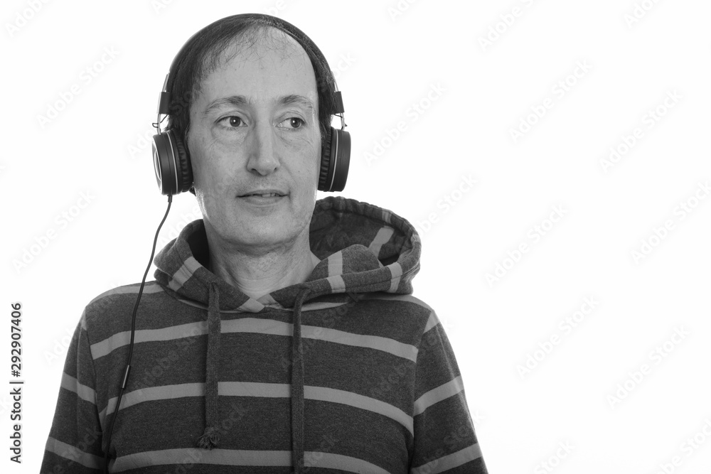 Studio shot of thoughtful happy mature man smiling while listening to music Studio shot of thoughtful happy mature man smiling while listening to music