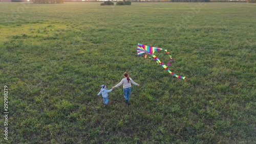 The mother and boy run with a kite on a green field. Laughter and joy, festive mood. Autumn,Sunset