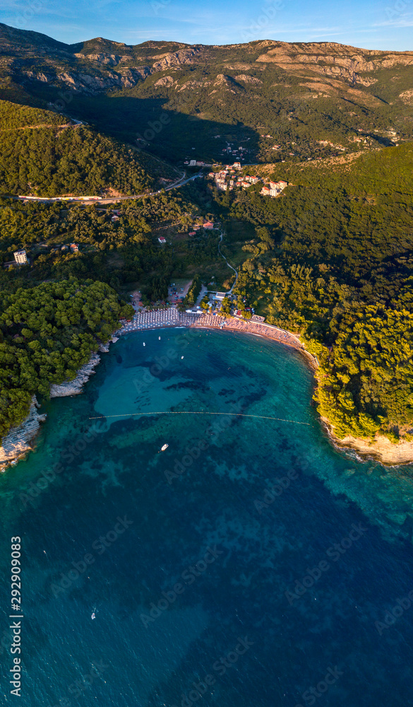 Aerial view of Lucice beach, one of the most beautiful sandy beaches at Montenegrin coast. Umbrellas and bathers at sunset. Seabed, (located next to Petrovac city). Montenegro