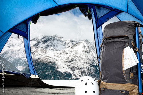 Winter backpack in blue tent and mountains landscape 
