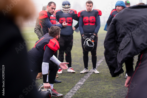 american football player discussing strategy with his team