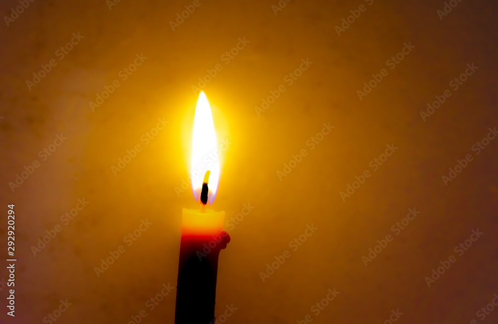 Burning candle in the dark with a dark background.