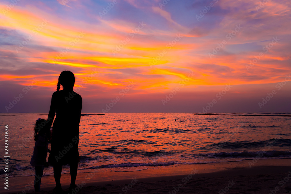Silhouette girl with younger sister stand on the beach with twilight colorful sky on sea in sunset or sunrise time Silhouette girl with younger sister stand on the beach with twilight colorful sky on sea in sunset or sunrise time