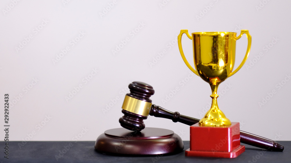 Judge's gavel and trophy on white background. Symbol for jurisdiction. Law concept a wooden judges gavel on table in a courtroom or law enforcement office Judge's gavel and trophy on white background. Symbol for jurisdiction. Law concept a wooden judges gavel on table in a courtroom or law enforcement office