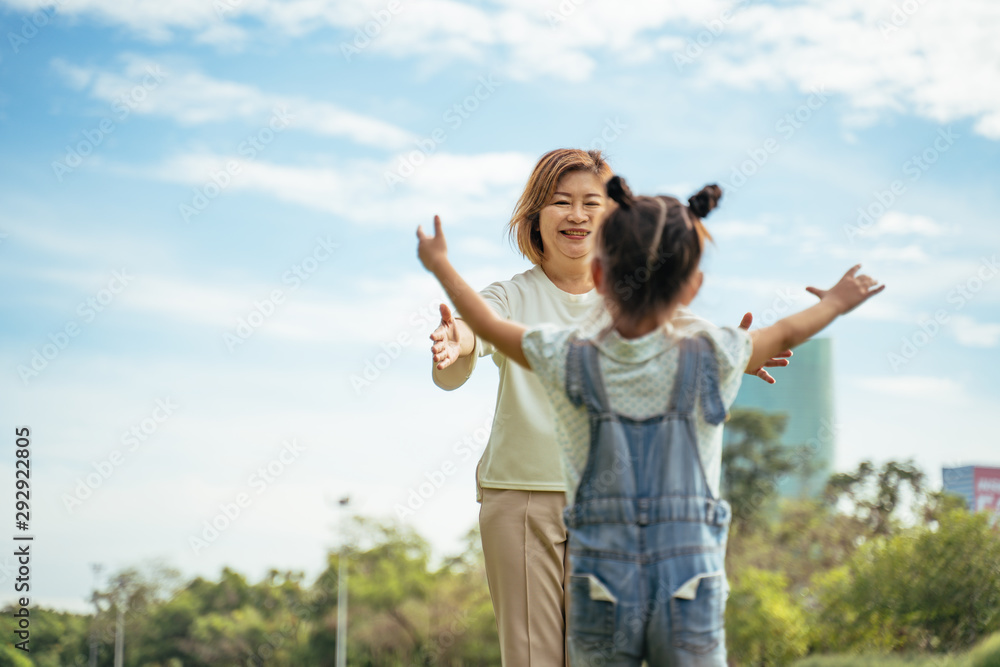 Nice little girl run to grandmother's hug in park.Grandmother and grand daughter enjoying sunny garden holiday together, outdoors space, leisure lifestyle,happy teaching with flare light sky in park. Nice little girl run to grandmother's hug in park.Grandmother and grand daughter enjoying sunny garden holiday together, outdoors space, leisure lifestyle,happy teaching with flare light sky in park.