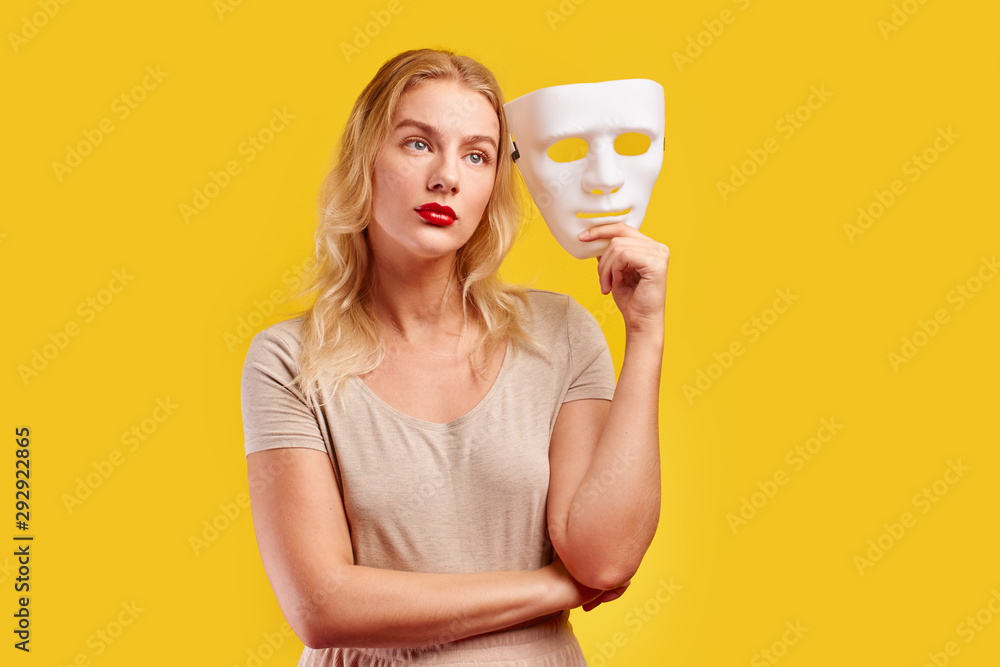 Emotional female person with white mask on yellow background. Internet fraud concept, anonymous, incognito, bipolar personality disorder, hypocrisy. Emotional female person with white mask on yellow background. Internet fraud concept, anonymous, incognito, bipolar personality disorder, hypocrisy.
