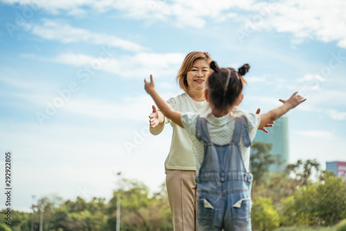 Nice little girl run to grandmother's hug in park.Grandmother and grand daughter enjoying sunny garden holiday together, outdoors space, leisure lifestyle,happy teaching with flare light sky in park.