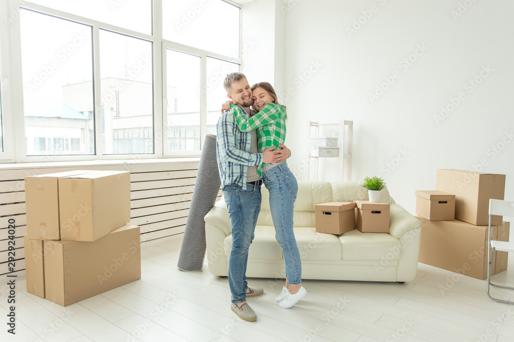 Loving young couple embracing rejoicing in moving to their new home. The concept of moving and housewarming of young family. Loving young couple embracing rejoicing in moving to their new home. The concept of moving and housewarming of young family.