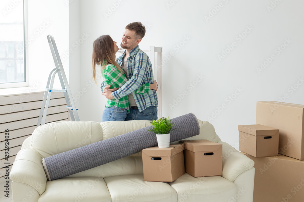 Young couple in denim pants embracing rejoicing in their new apartment during the move. The concept of housewarming and credit for new housing. Young couple in denim pants embracing rejoicing in their new apartment during the move. The concept of housewarming and credit for new housing.