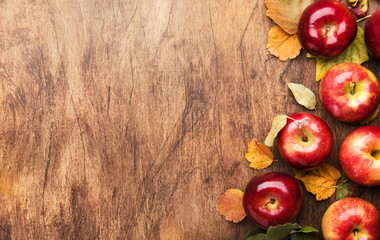 Autumn food background. Ripe apples with nuts, fallen leaves and cinnamon on rustic wooden table. Top view. Copy space