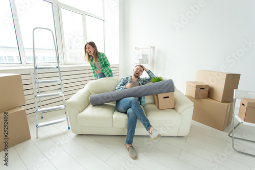 Positive crazy cheerful couple rejoices in moving their new apartment sitting in the living room with their belongings. Concept of housewarming and mortgages for a young family. © satura_