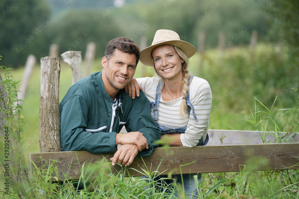 Portrait of smiling couple of farmer standing by fence Portrait of smiling couple of farmer standing by fence