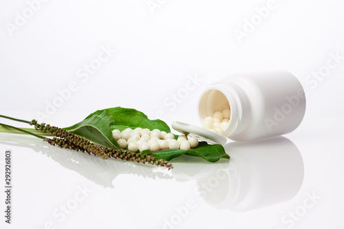 Bottle with homeopathic pills on green plant leaf. Homeopathy, naturopathy and alternative herbal medicine
