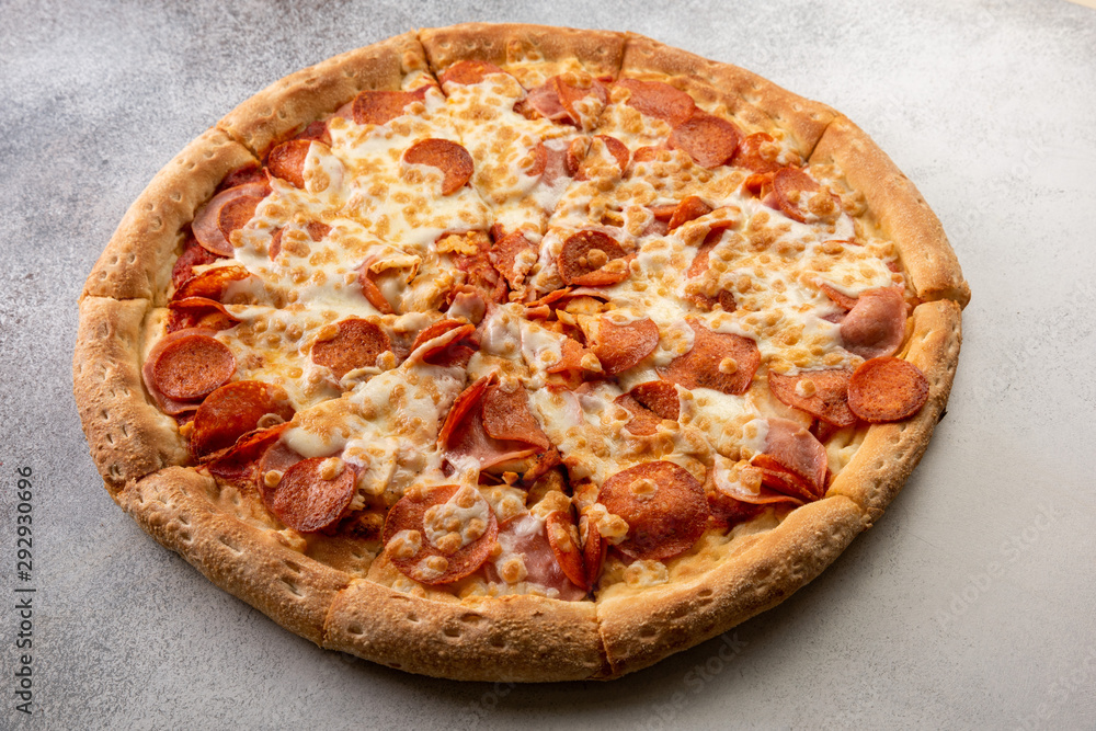 Delicious hot homemade Pepperoni pizza on the wooden table. Pepperoni Pizza - Fresh homemade pizza with pepperoni, cheese and tomato sauce on rustic black stone background with copy space.