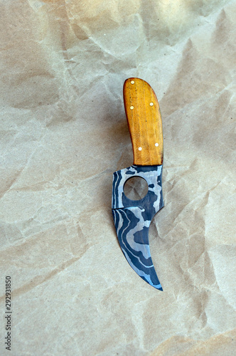 A rather unique skinner damascus knife with a curved blade and a finger hole. This one has a pretty hedge handle. Bokeh. photo