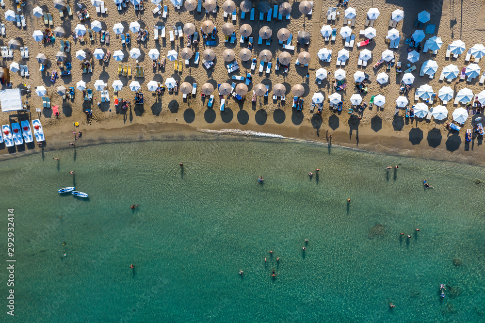 Aerial top view photo of sun beds and umbrellas in popular tropical paradise deep turquoise Mediterranean sandy crowded beach.