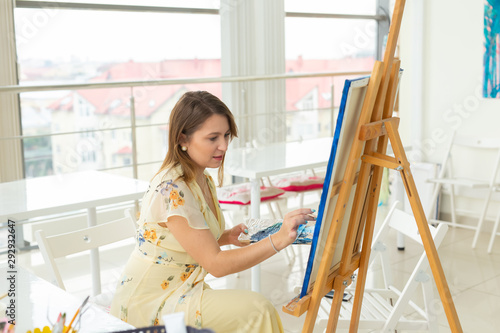 Art class and drawing concept - Woman artist working on painting in studio.