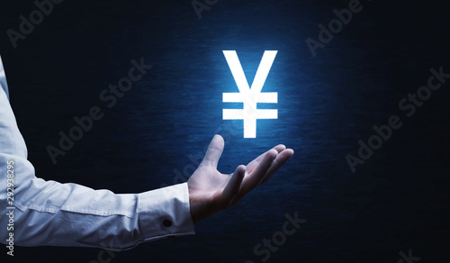 Male hand holding yen currency symbol. photo