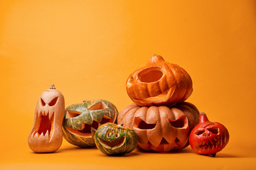 Photo of creepy halloween pumpkins on empty orange background.
