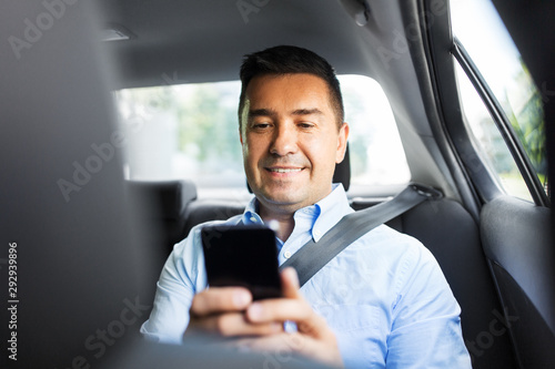 transport, business and communication concept - smiling male passenger or businessman using smartphone on back seat of taxi car © Syda Productions