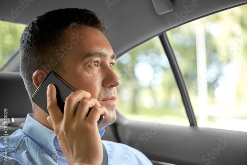 transport, communication and business concept - male passenger or businessman calling on smartphone on back seat of taxi car