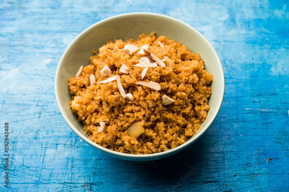 Fototapeta premium Wheat Laapsi/Lapsi/Shira/Halwa is an Indian sweet dish made of broken wheat or Daliya pieces and ghee along with nuts, raisins and dried fruits. It's a healthy food. served in a bowl, selective focus