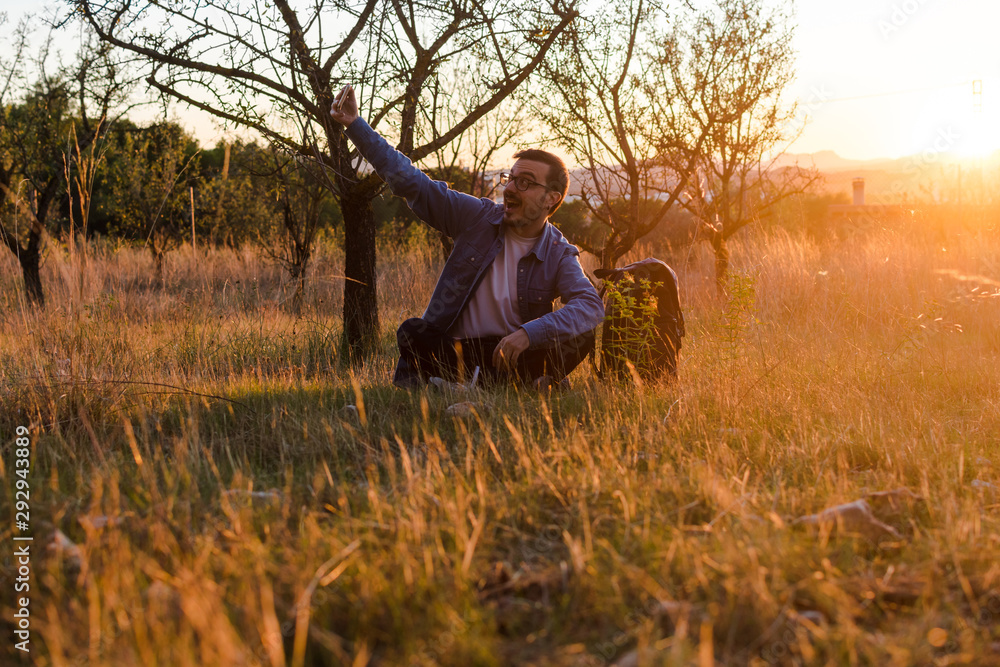 Young man is using his smartphone in a meadow Young man is using his smartphone in a meadow