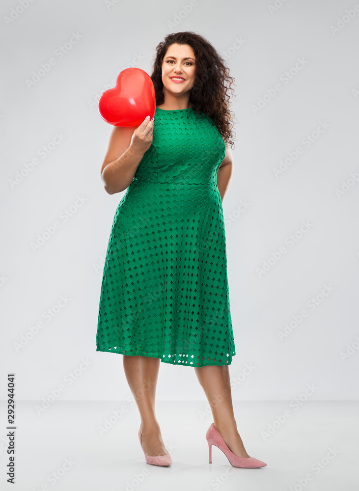 valentine's day, people and love concept - happy woman in green dress holding red heart shaped balloon over grey background valentine's day, people and love concept - happy woman in green dress holding red heart shaped balloon over grey background