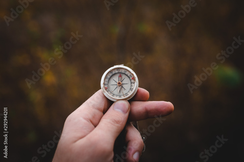 Man hand holding a old compass with broken glass. Travel concept, path selection, navigation, tourism, hiking. Autumn background. crack on the glass as disappointment and cancellation of plans.