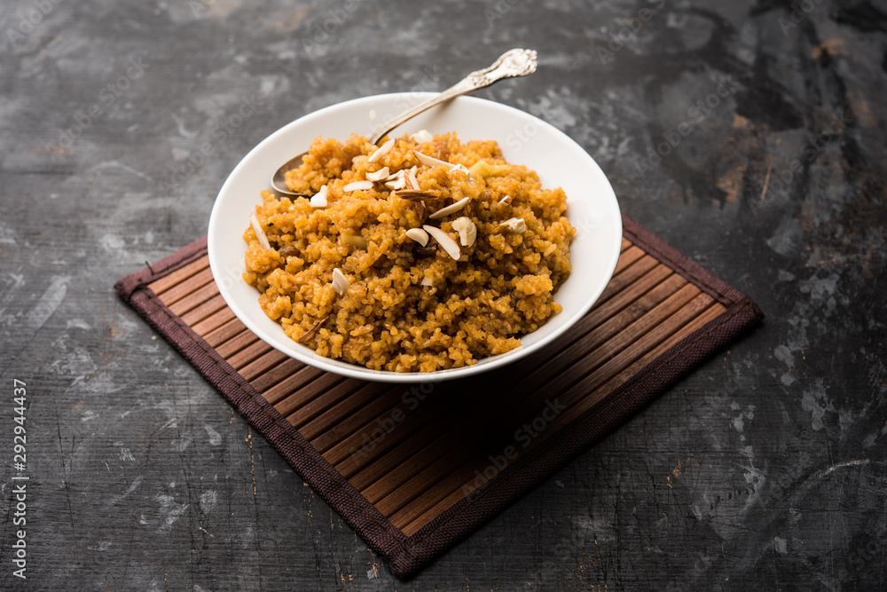 Fototapeta premium Wheat Laapsi/Lapsi/Shira/Halwa is an Indian sweet dish made of broken wheat or Daliya pieces and ghee along with nuts, raisins and dried fruits. It's a healthy food. served in a bowl, selective focus