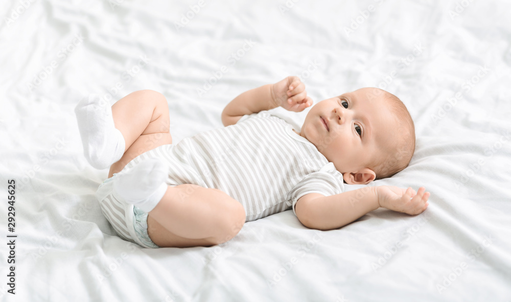 Cute little baby lying on bed and looking to camera Cute little baby lying on bed and looking to camera
