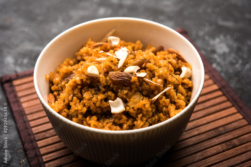 Wheat Laapsi/Lapsi/Shira/Halwa is an Indian sweet dish made of broken wheat or Daliya pieces and ghee along with nuts, raisins and dried fruits. It's a healthy food. served in a bowl, selective focus Wheat Laapsi/Lapsi/Shira/Halwa is an Indian sweet dish made of broken wheat or Daliya pieces and ghee along with nuts, raisins and dried fruits. It's a healthy food. served in a bowl, selective focus