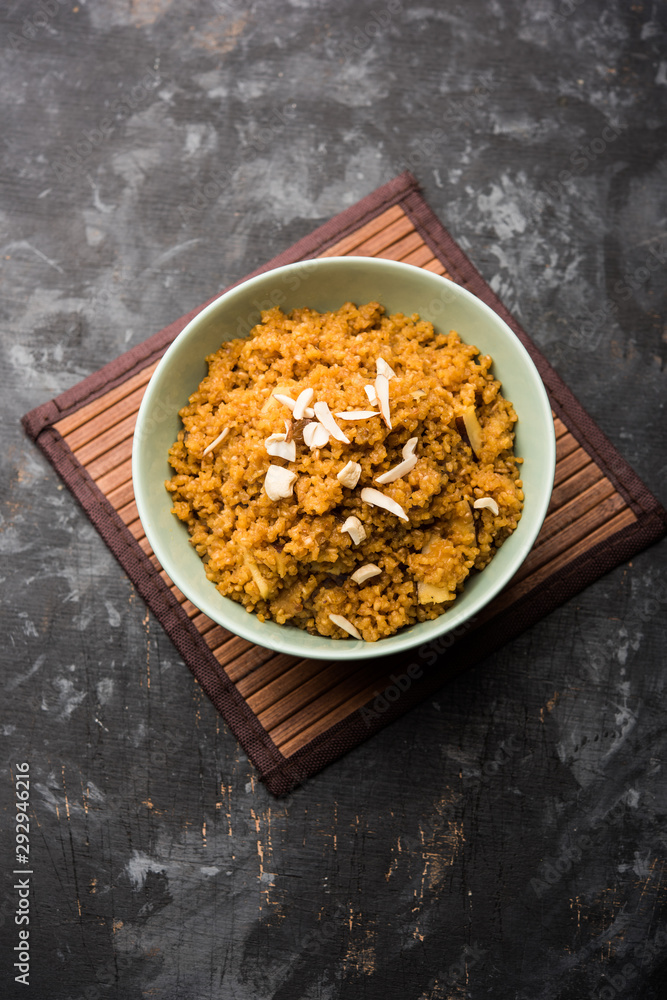 Fototapeta premium Wheat Laapsi/Lapsi/Shira/Halwa is an Indian sweet dish made of broken wheat or Daliya pieces and ghee along with nuts, raisins and dried fruits. It's a healthy food. served in a bowl, selective focus