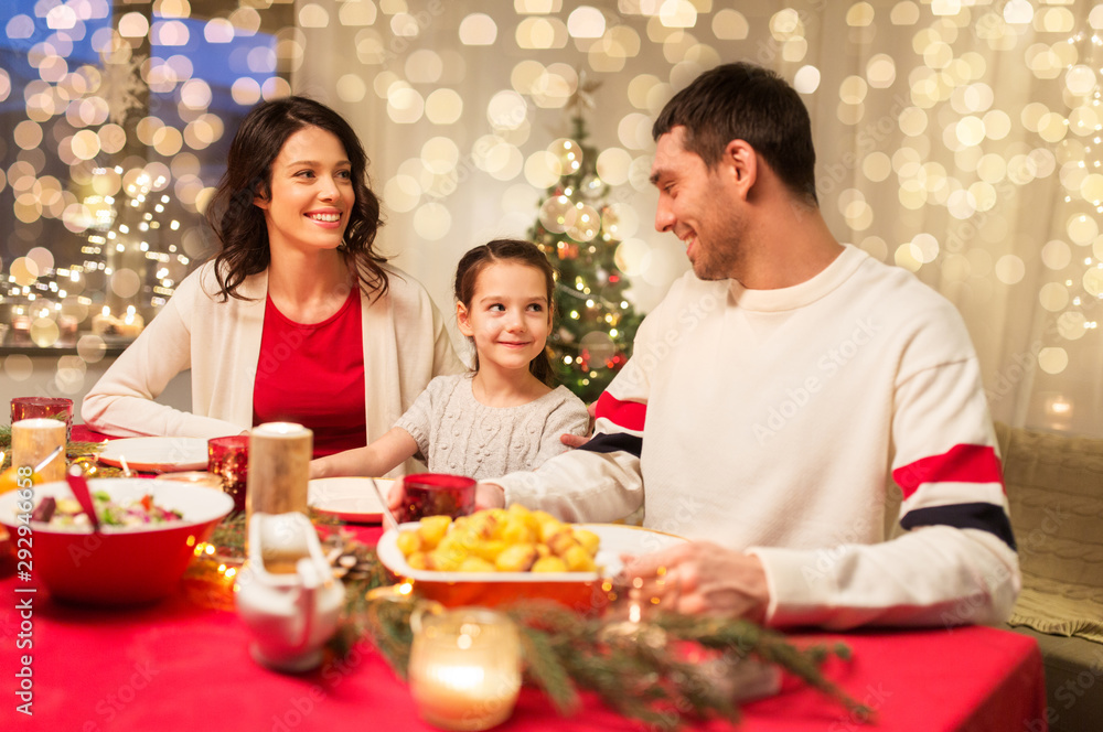 holidays, family and celebration concept - happy mother, father and little daughter having christmas dinner at home holidays, family and celebration concept - happy mother, father and little daughter having christmas dinner at home