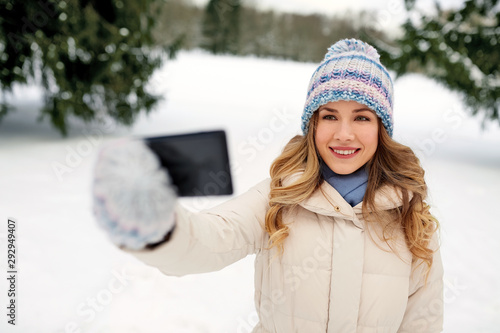 people, season and leisure concept - happy smiling woman taking selfie by smartphone in winter