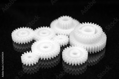 Fotografi Several white plastic gears on a black mirror background