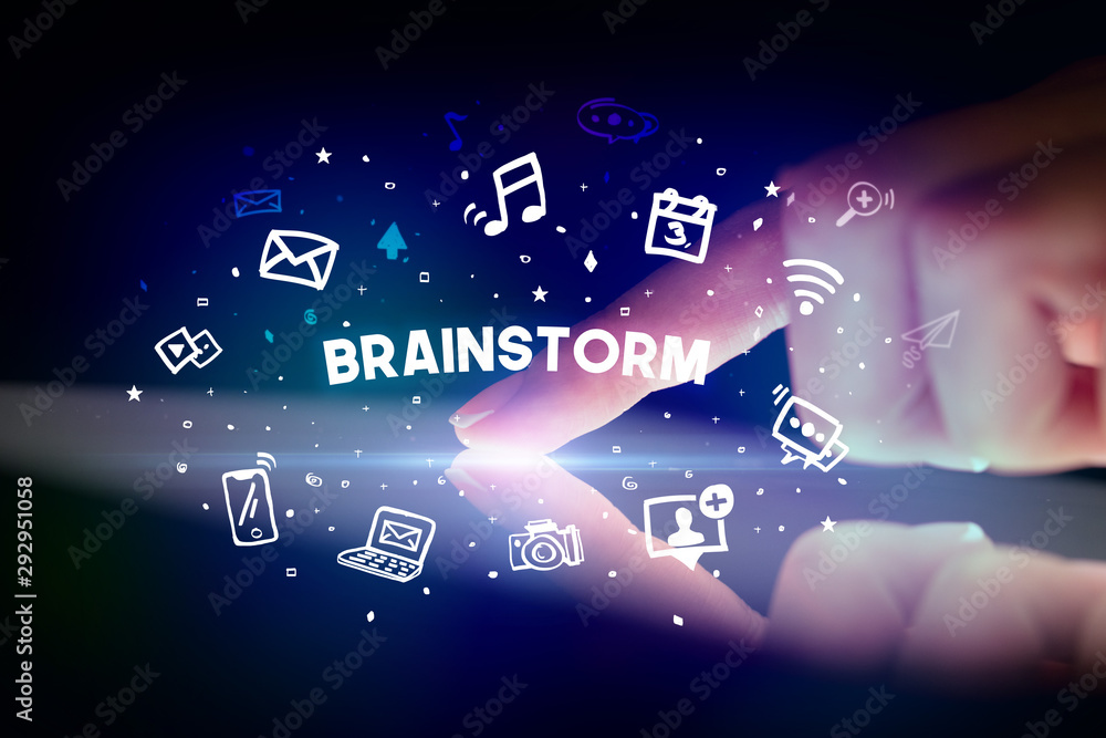 Finger touching tablet with drawn social media icons and BRAINSTORM inscription, social networking concept Finger touching tablet with drawn social media icons and BRAINSTORM inscription, social networking concept