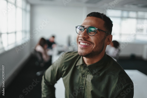 Portrait of a handsome casual businessman wearing black eyeglasses in office smiling photo