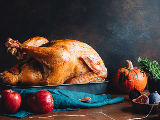 Festive table for Thanksgiving Holiday with whole roasted turkey with apple, pumpkin, figs and herbs in a mortar.